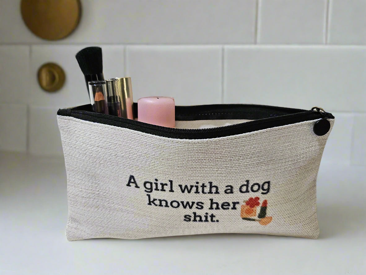 Cosmetic bag with text 'A girl with a dog knows her shit' on a white background